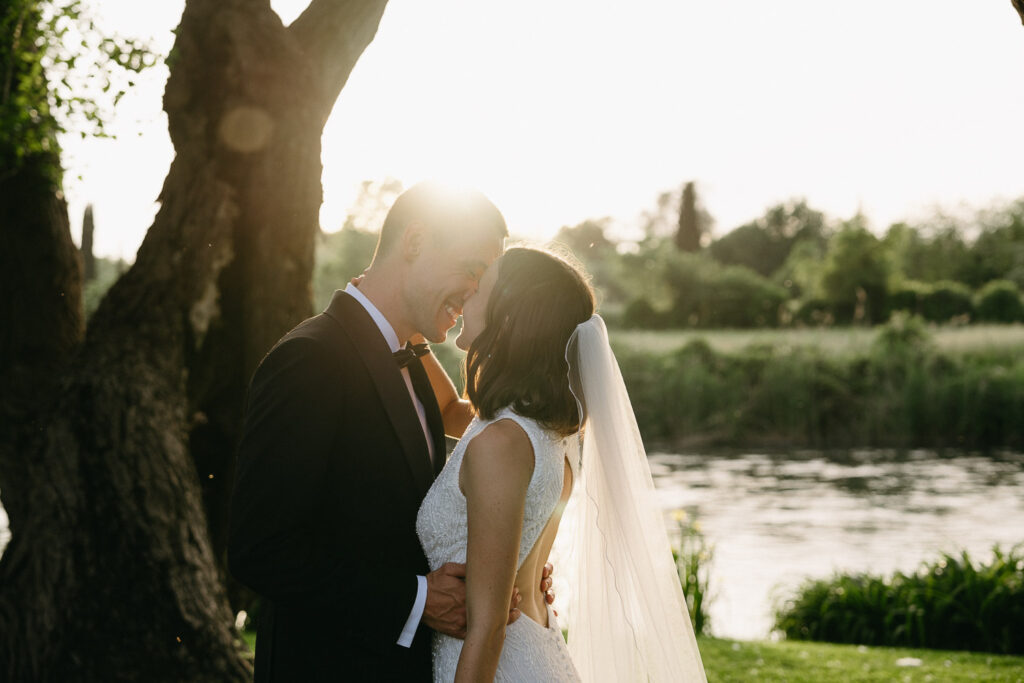 Newlyweds smiling and touching foreheads in soft evening light