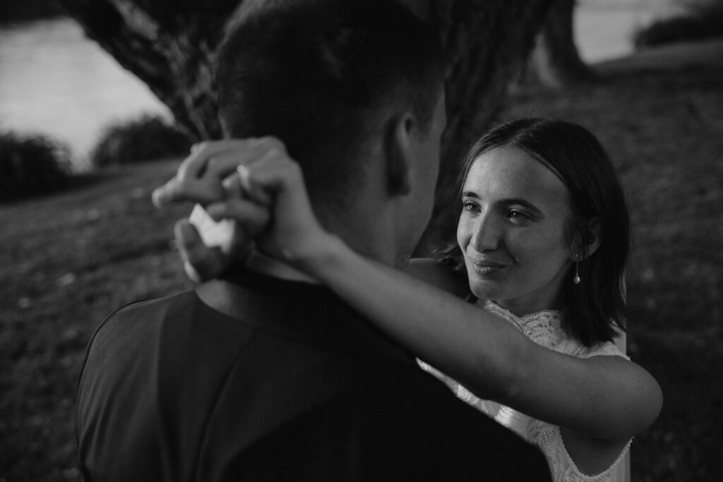 Emotive black-and-white moment between newlyweds at the riverside in italy