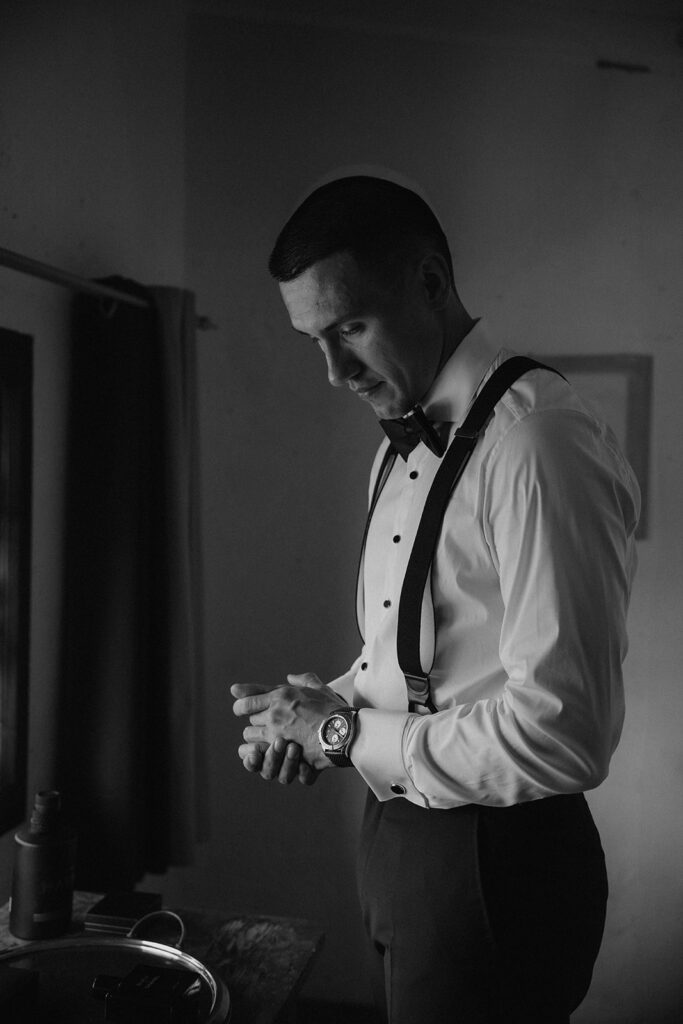 Black and white photo of groom dressing on wedding morning at La Finestra Sul Fiume