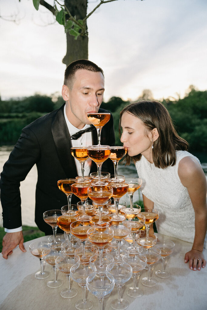 Bride and groom sipping from champagne tower in golden light at italian wedding