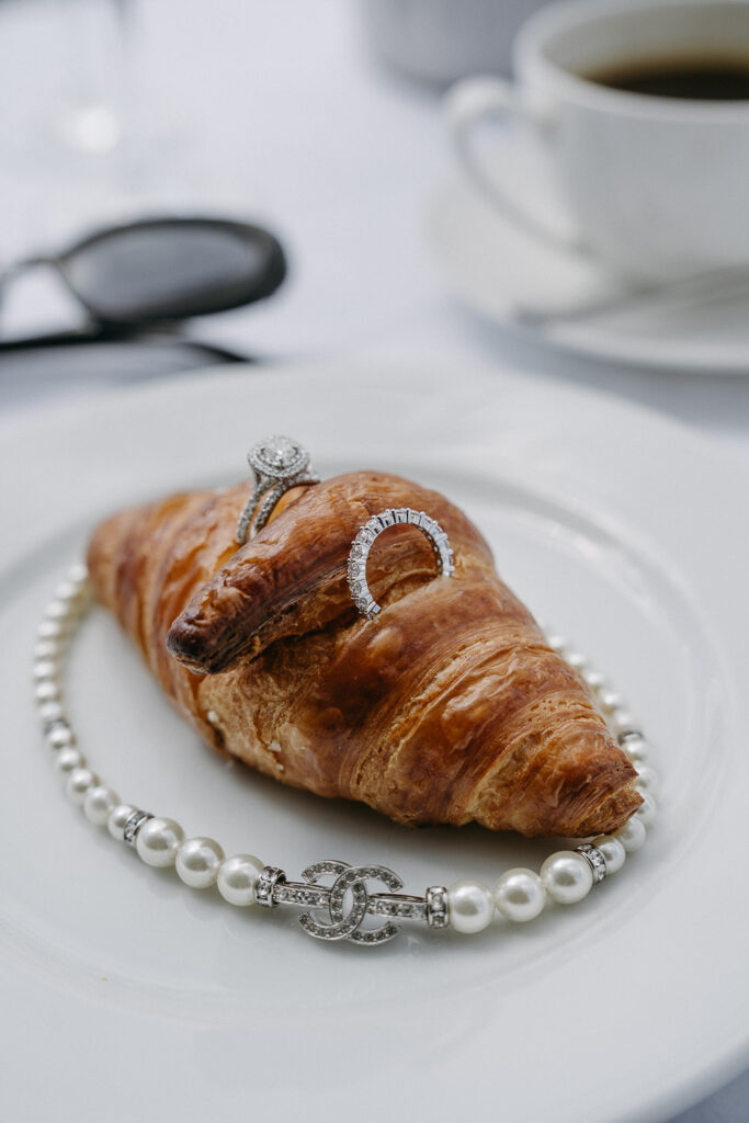 Tiffanys Ehering und Chanel Perlenkette auf Croissant bei Hochzeitsfrühstück am Tegernsee
